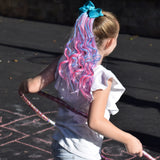 Girl wearing curly pink and teal hair extensions with bow